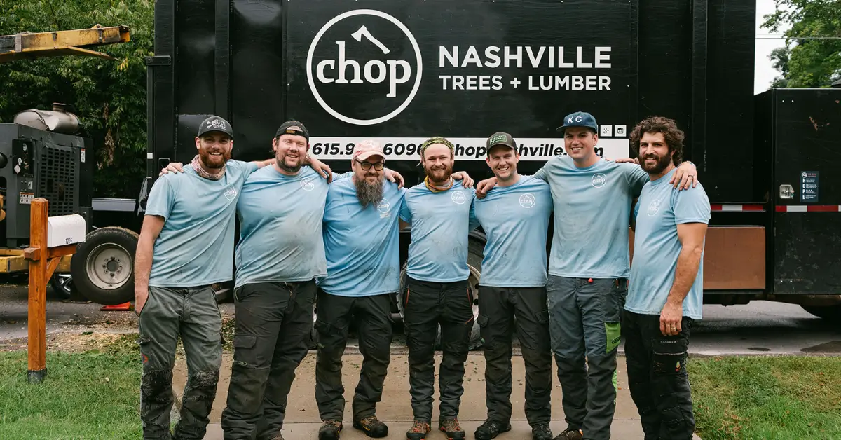 Seven Chop Nashville crew members standing arm in arm in front of the company truck