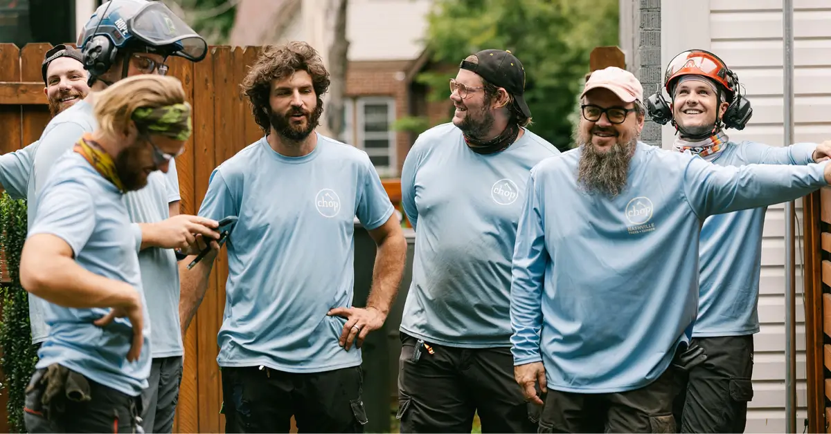 Chop Nashville crew members laughing together beside a wooden fence