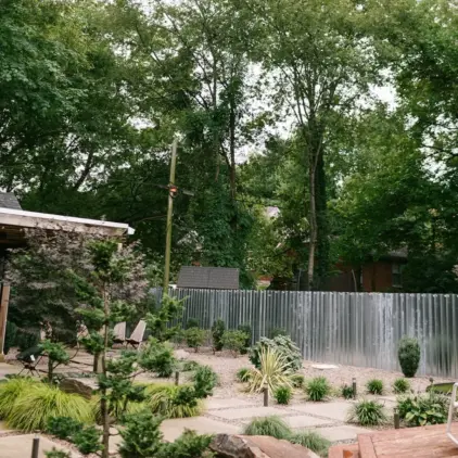 Landscaped backyard with a stone path and tall trees